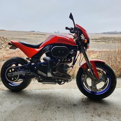 Custom red and blue Buell motorcycle parked outside the shop