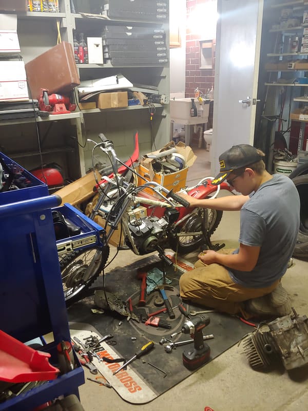 Technician working on a vintage dirt bike engine in the Motorcycle Medic shop